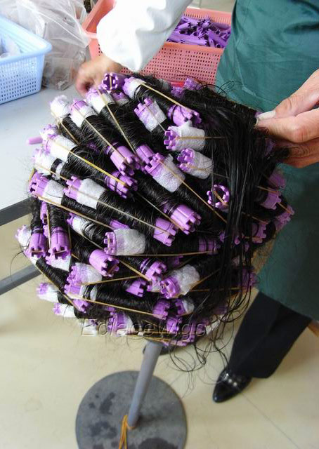 a worker is curling human hair wig